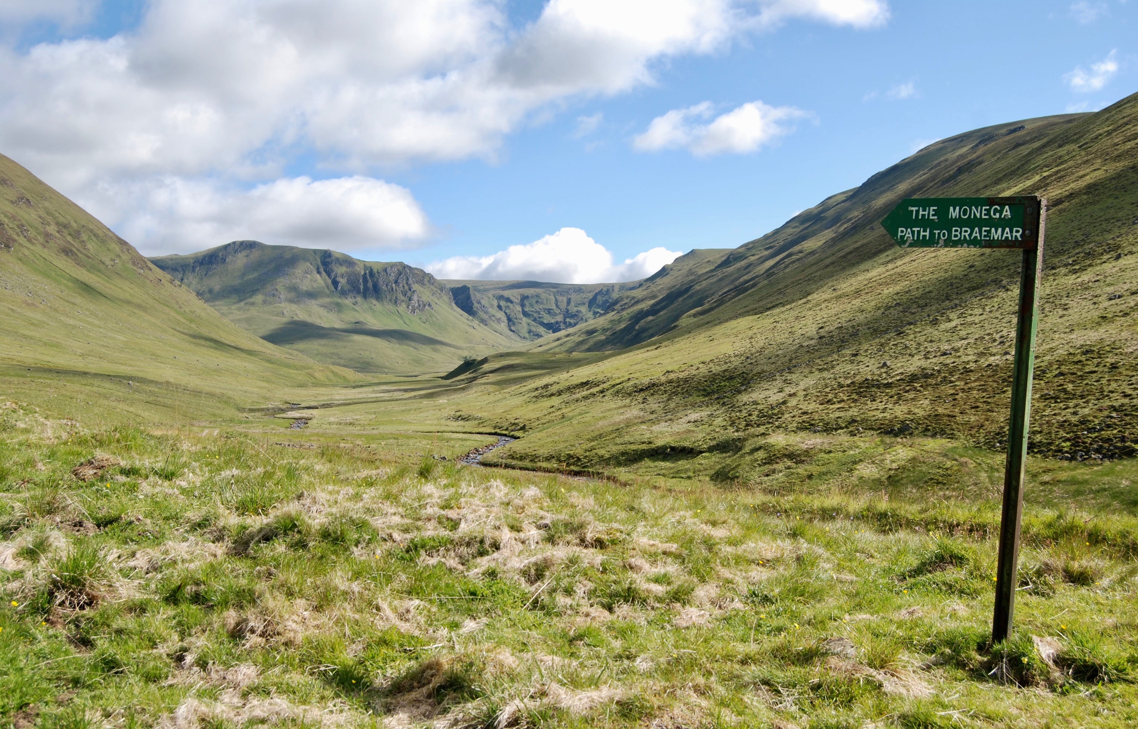 THE WAY AHEAD: Sign pointing to the start of the Monega Path with the impressive faces of Caenlochan in distance