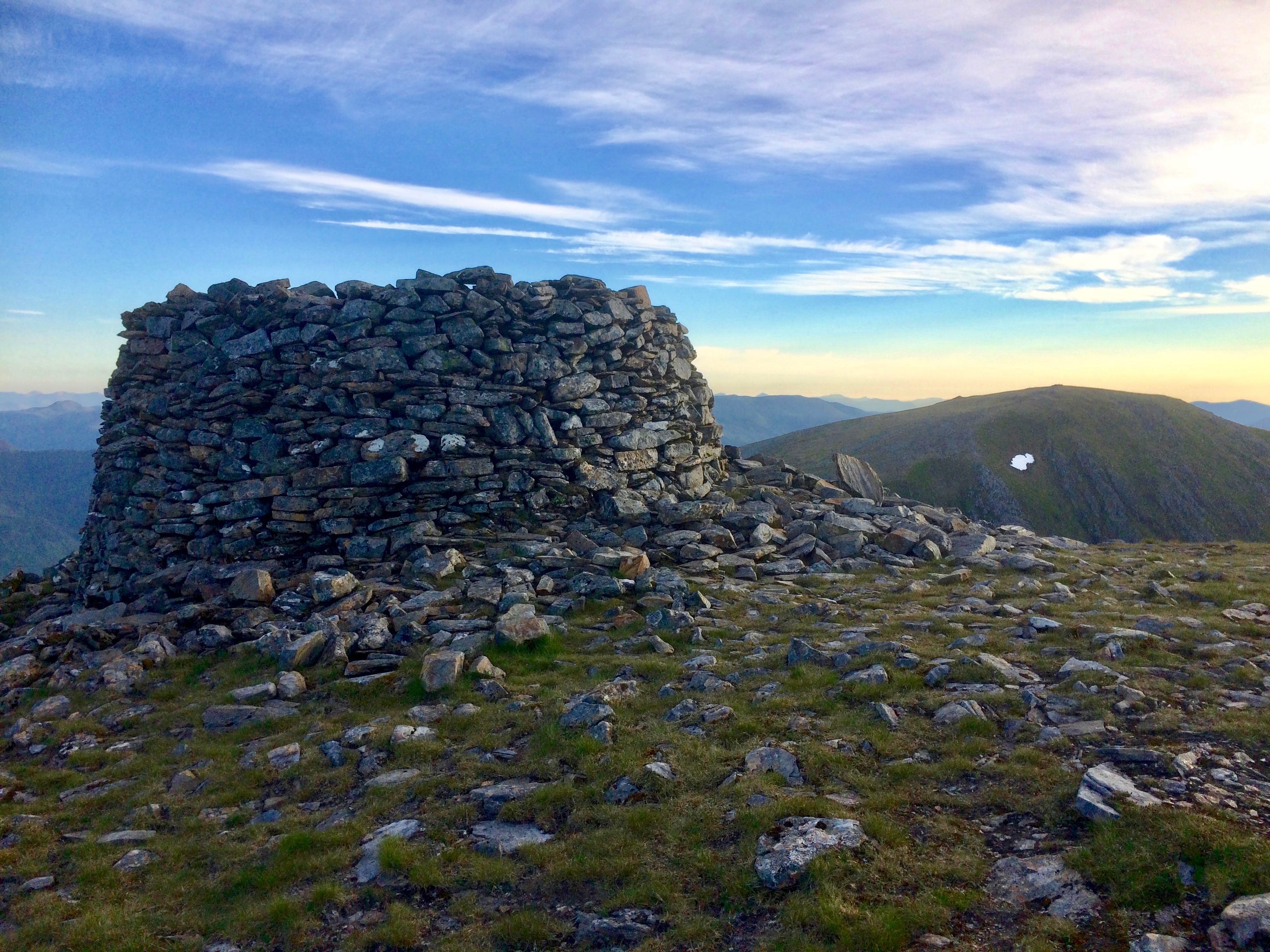 ROCKS OF AGES; Looking through the morning sky from the huge circular cairn on Mam Sodhail to neighbouring Carn Eige